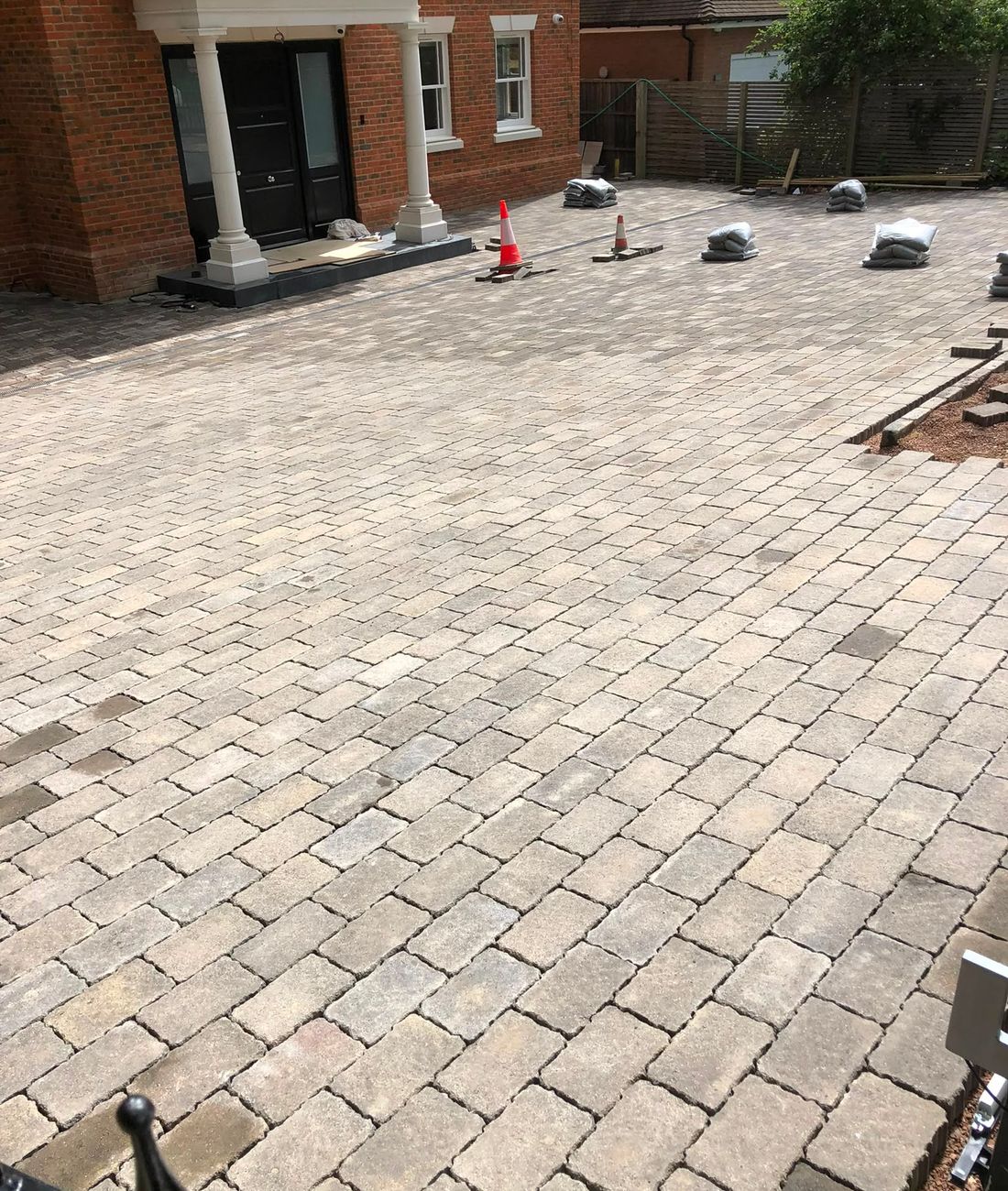 A porcelain patio and block paving meeting on a landscaped project