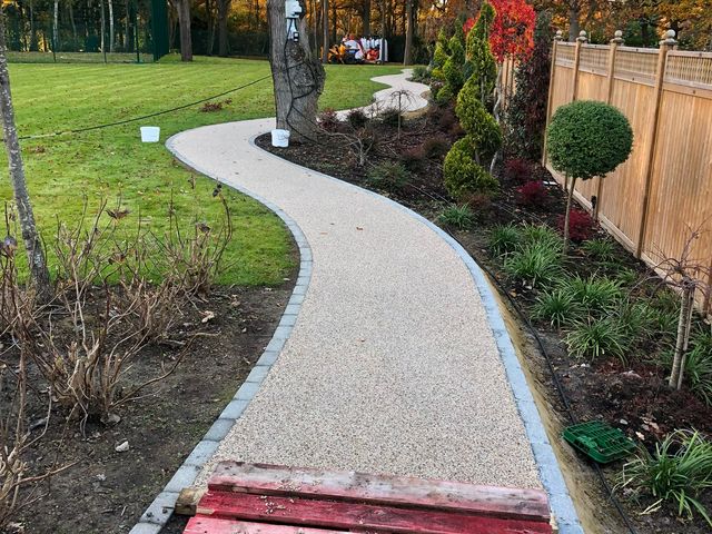 A curved resin-bound garden path between planted borders