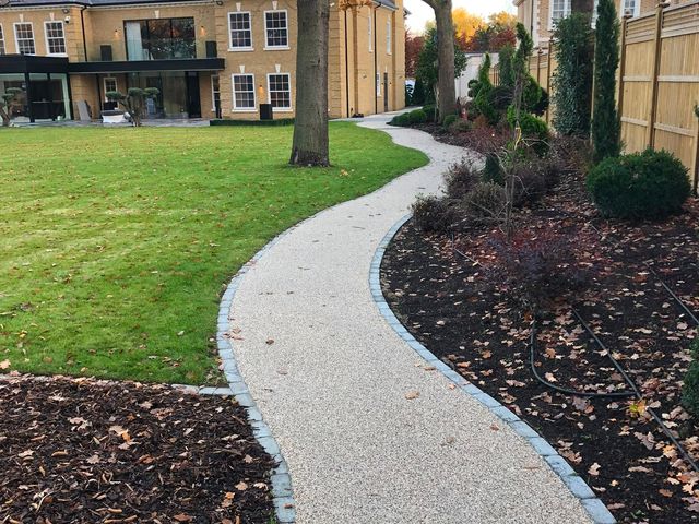 A resin-bound path leading through a garden to a house
